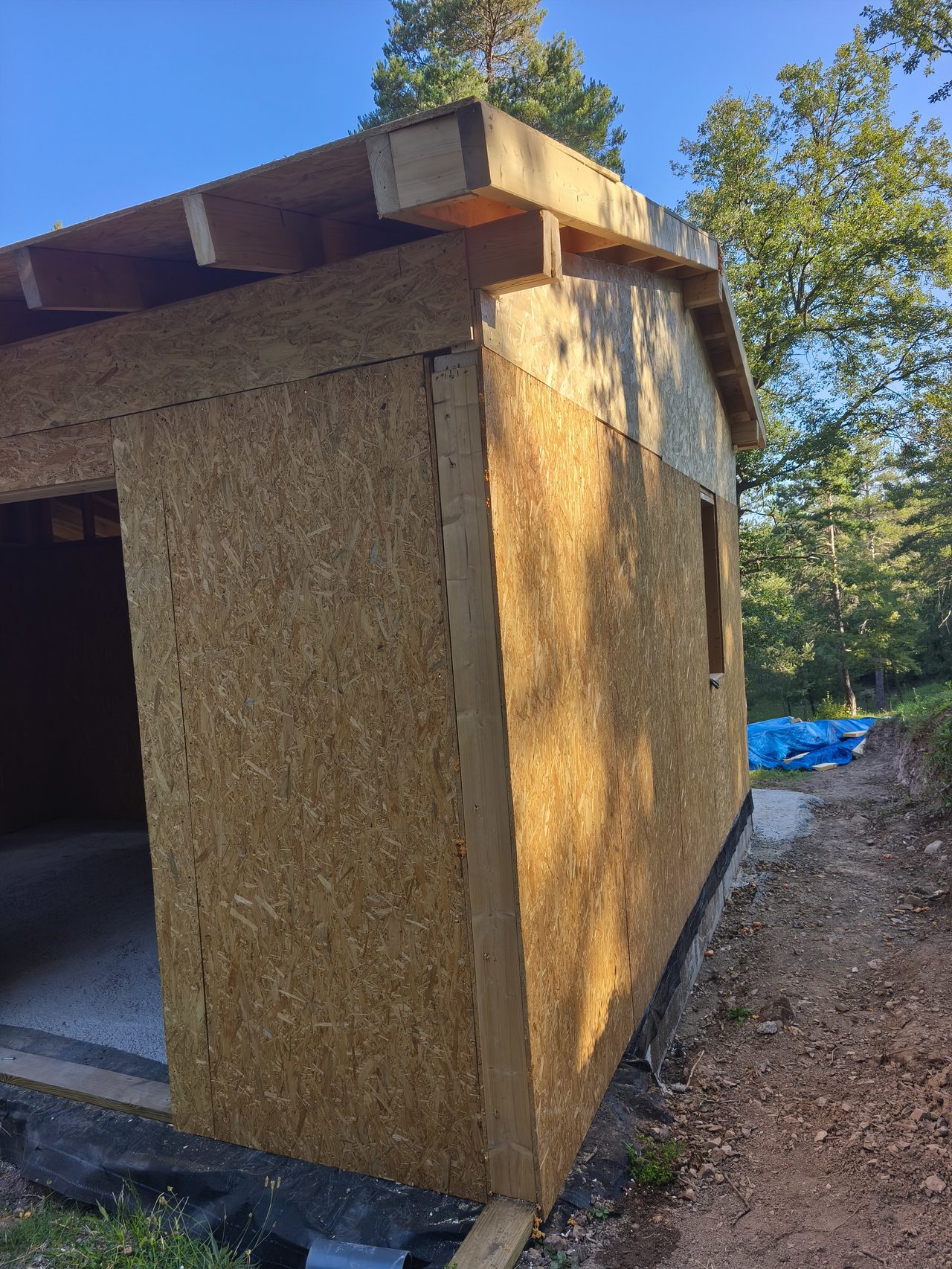 Corte de panel SIP con metro mostrando las tres capas: OSB exterior, núcleo EPS y OSB interior
